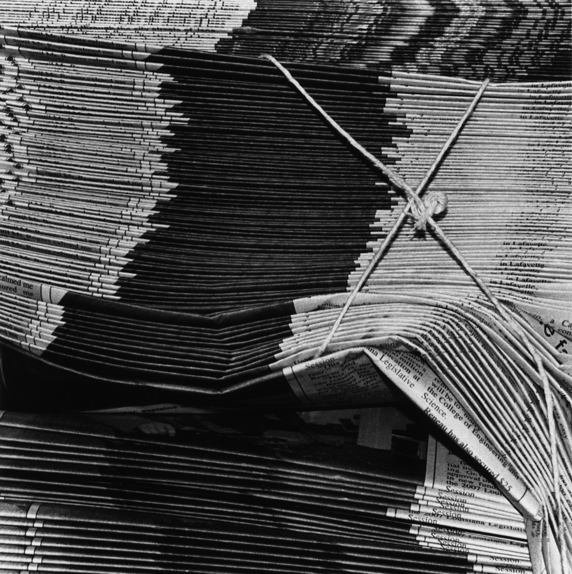 Close-up of stacks of newspapers bundled with string.