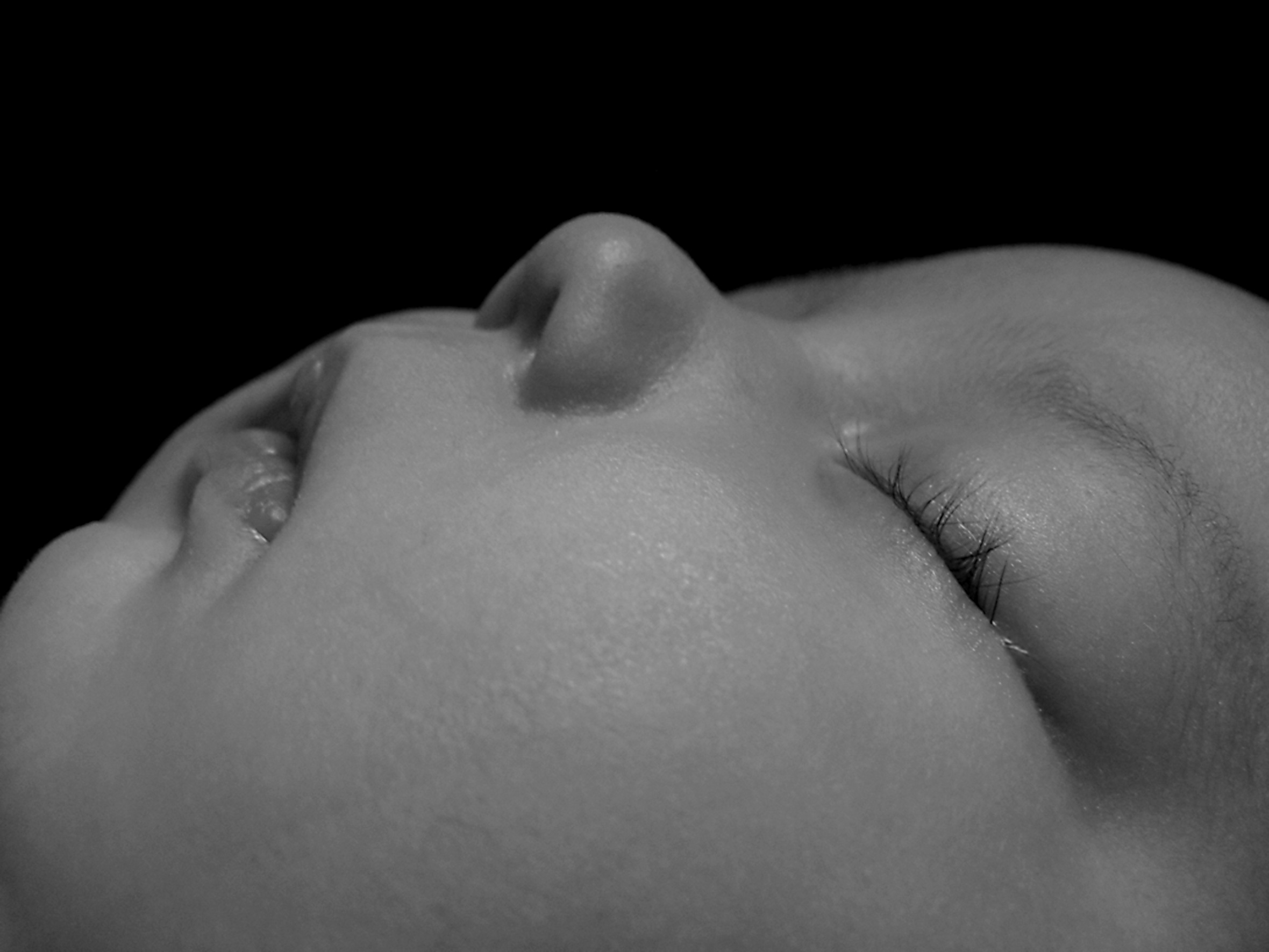 Close-up of an infant’s face who is sleeping on their back.