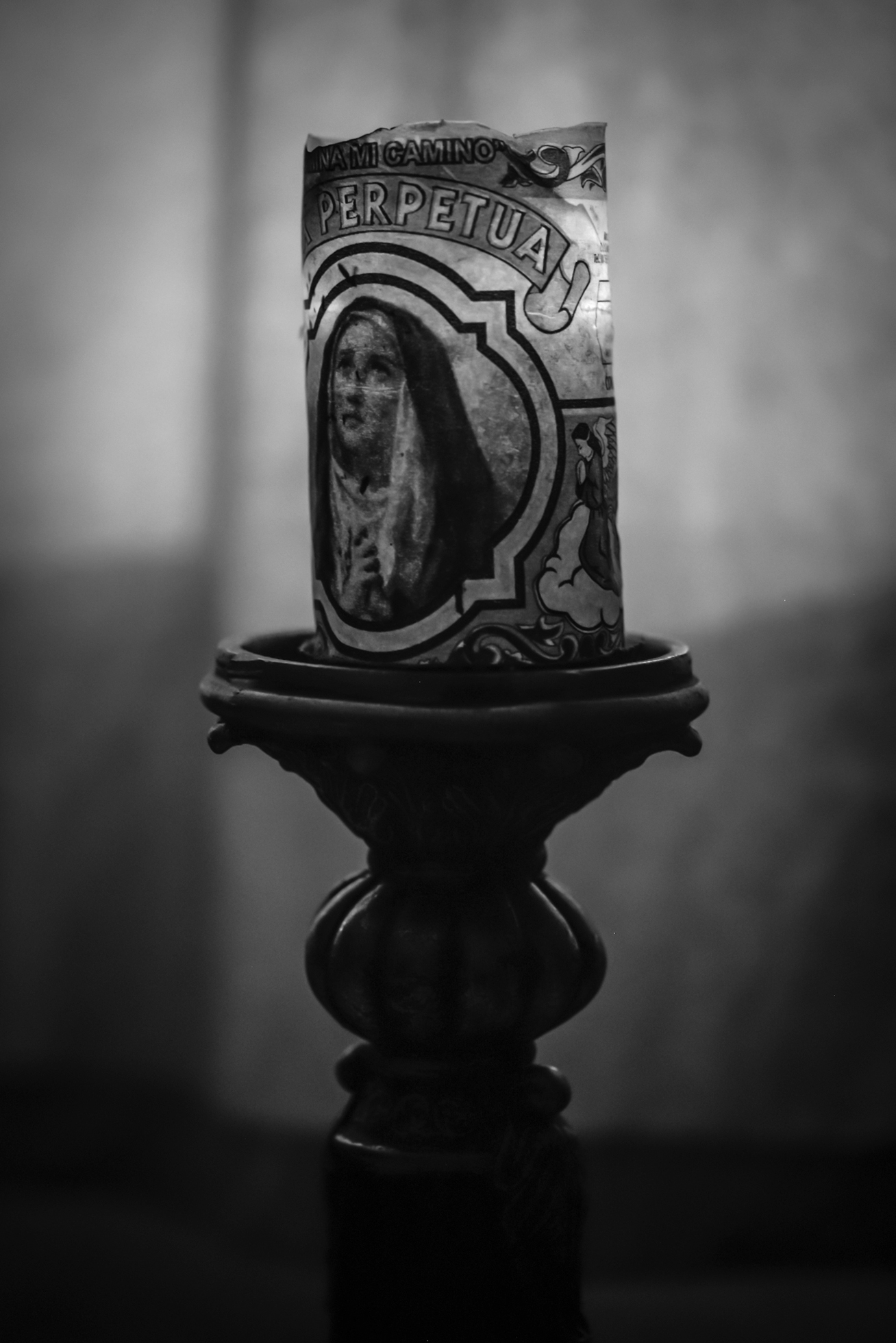 A votive candle that reads “Ilumina Mi Camino” (light my way) set on a pedestal.