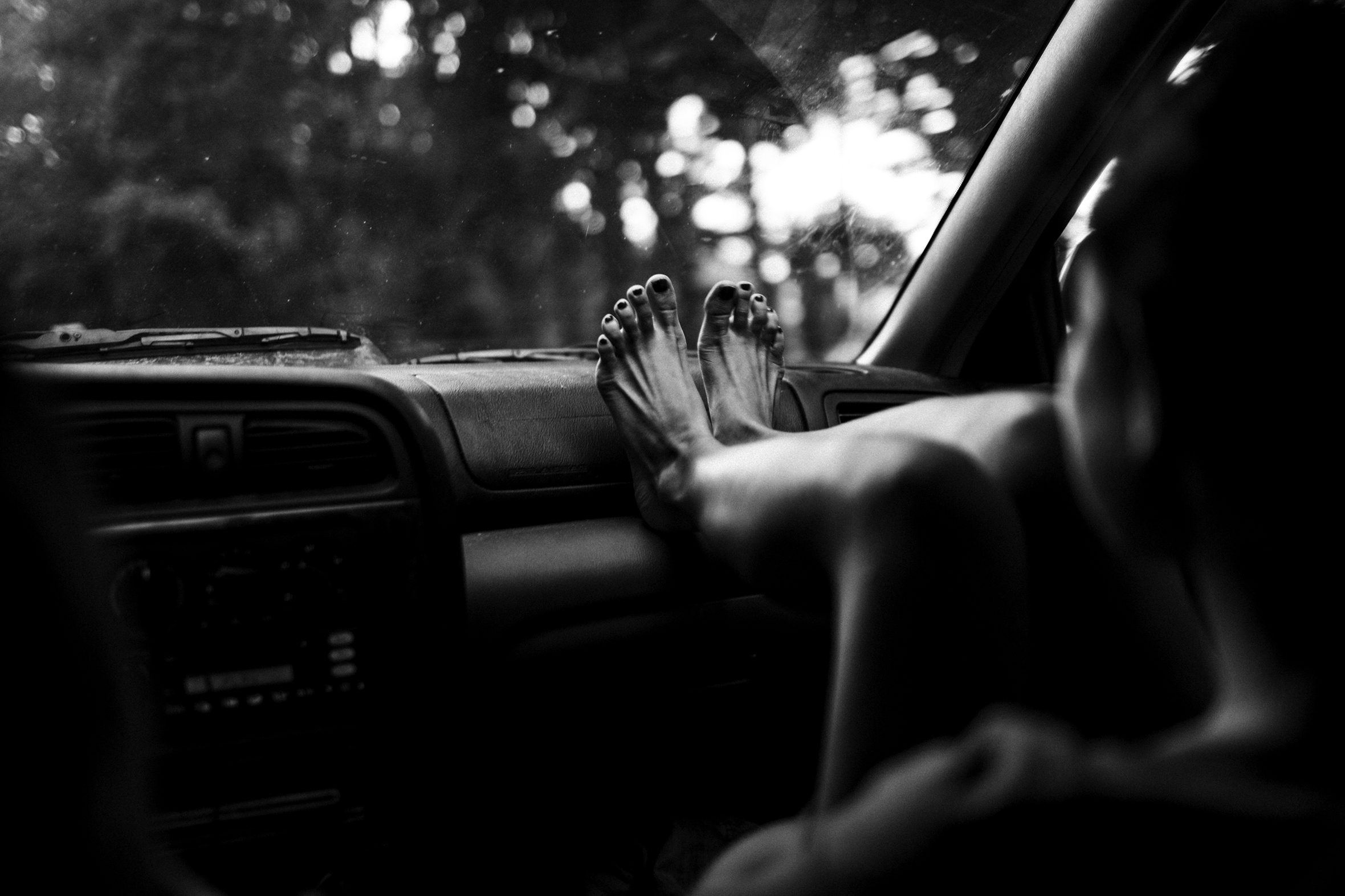 A person’s feet resting on the dashboard of a car