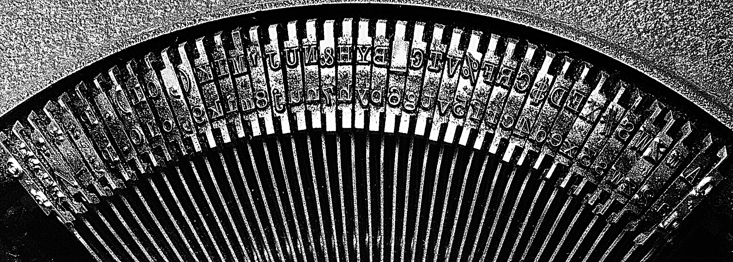 A top-down and close-up view of the type bars of an old-fashioned typewriter.