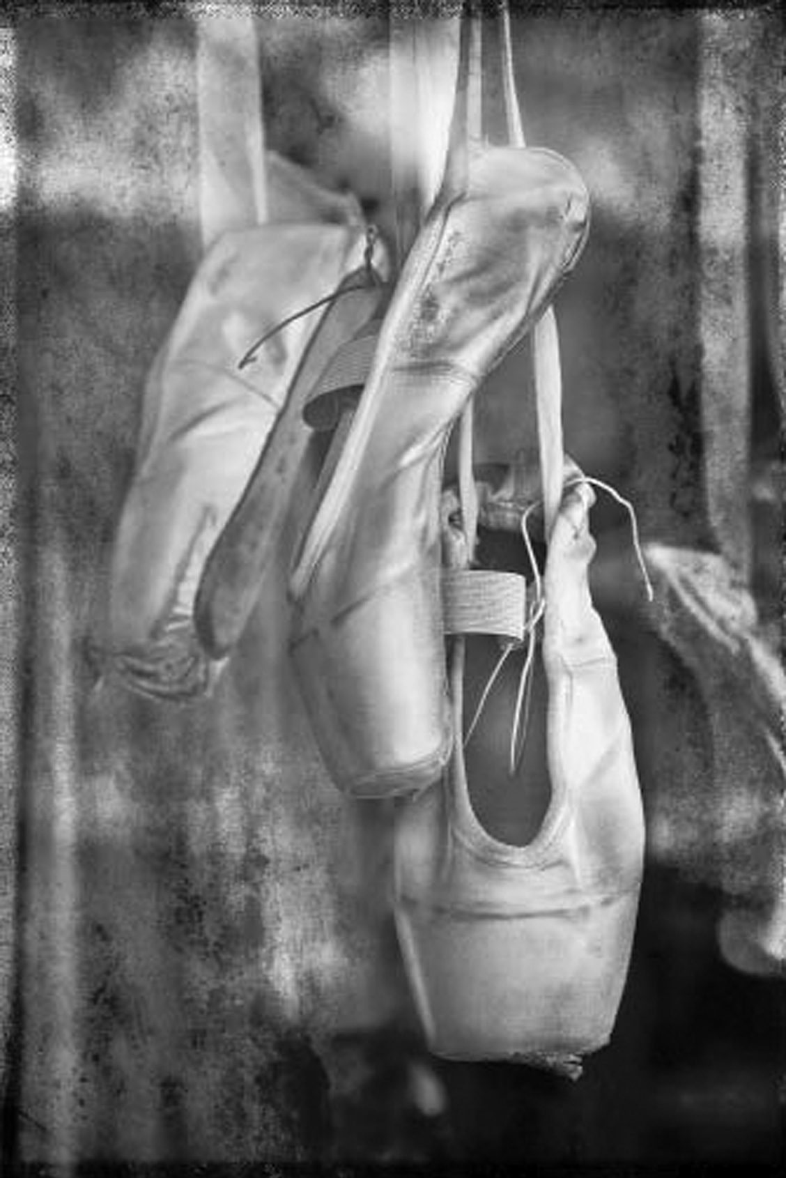 Worn ballet shoes of different sizes are seen hanging.