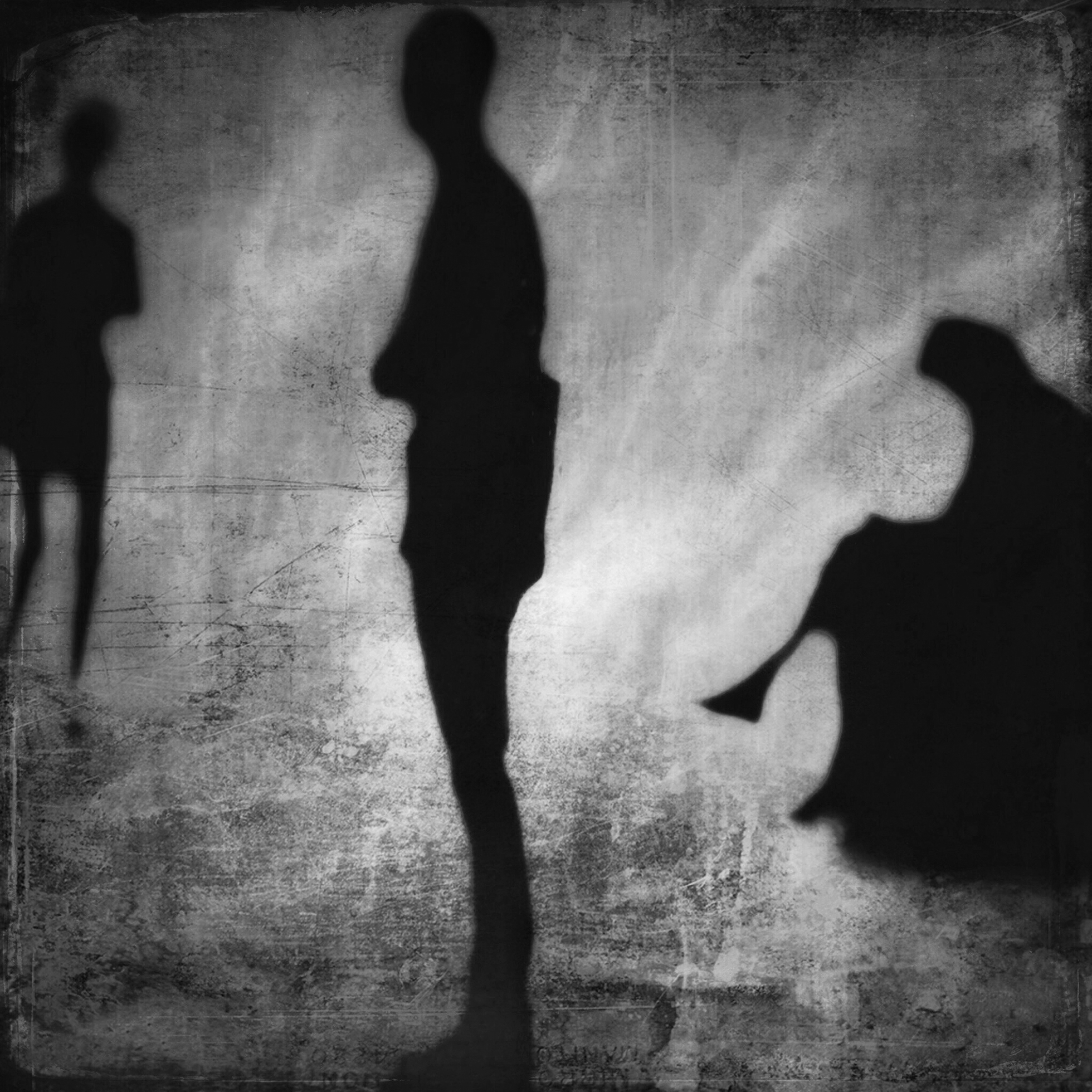 Three distorted, shadowy figures among a grunge background. The figure on the left is standing with their arms crossed. The figure in the center is standing in profile facing left. The figure on the right is sitting and looking down.