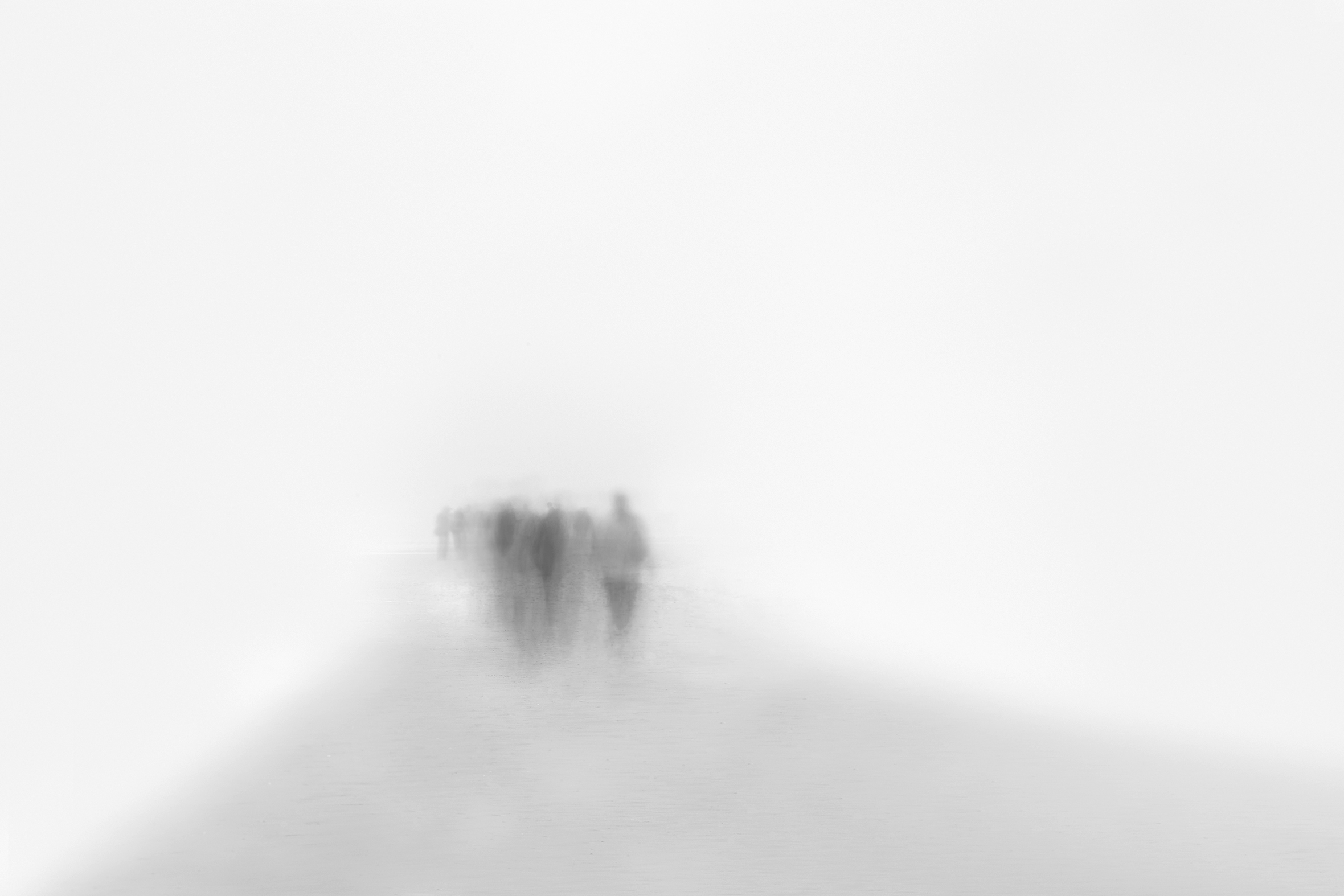 A small, tight grouping of faint, shadowy figures seem to be walking from the light gray foreground toward the opaque whiteness of the background that dominates the image.
