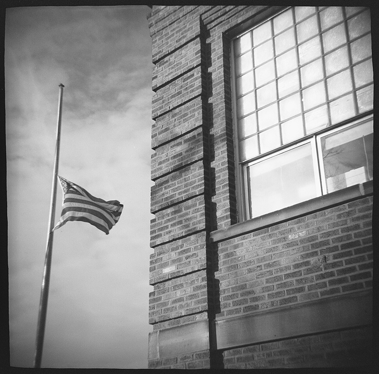 Outside a school building with the flag at half-mast.