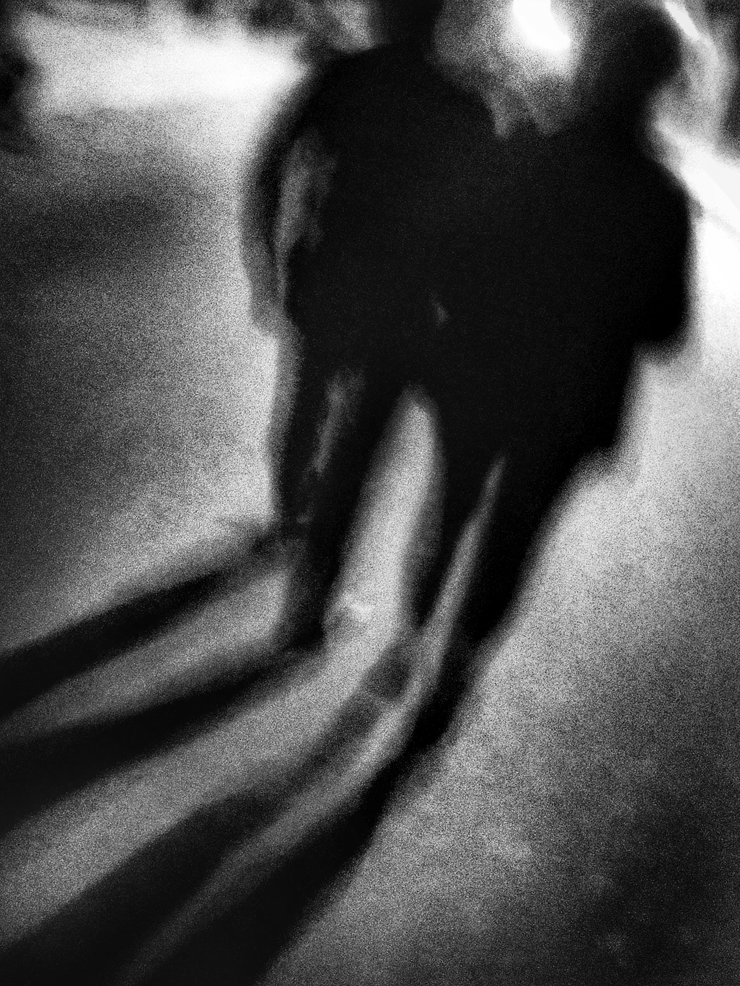 Two blurred, dark figures surrounded by light walk away toward a circular light leaving long shadows behind.