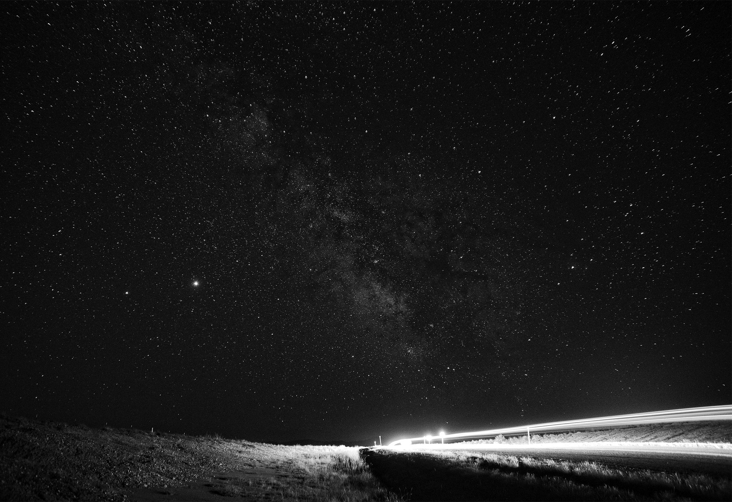 An isolated highway on a clear, starry night.