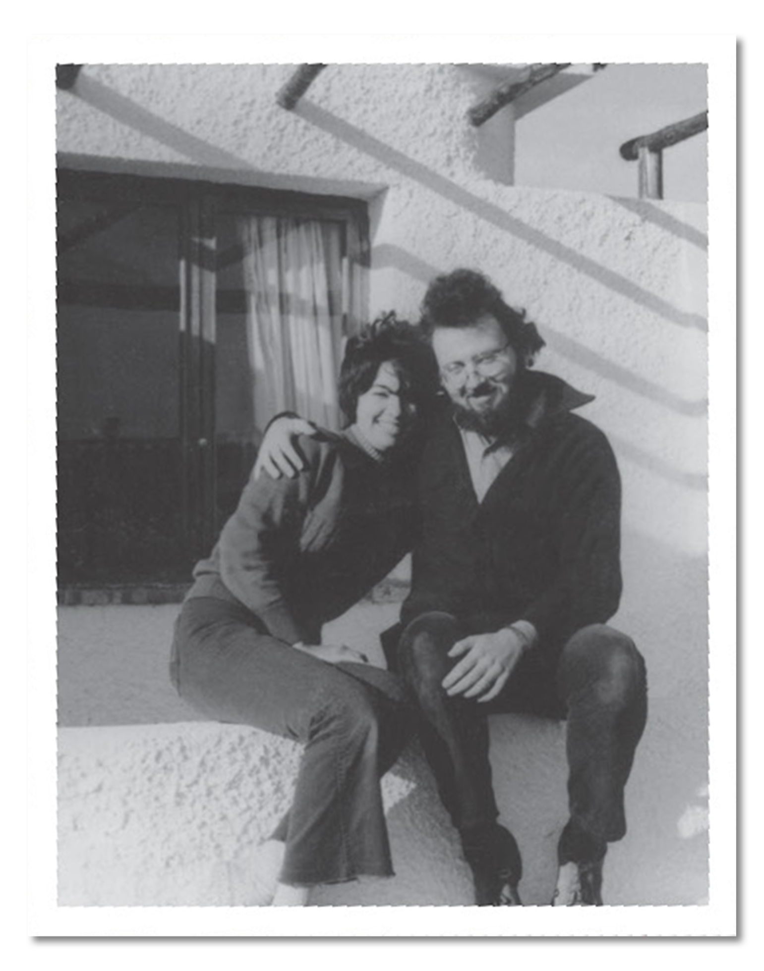 Sy Safransky and his first wife, Judy, are smiling and sitting closely together on white, stucco-looking steps at a property on the beach in Algeciras, Spain, in 1970. Sy has his arm around Judy’s shoulder.