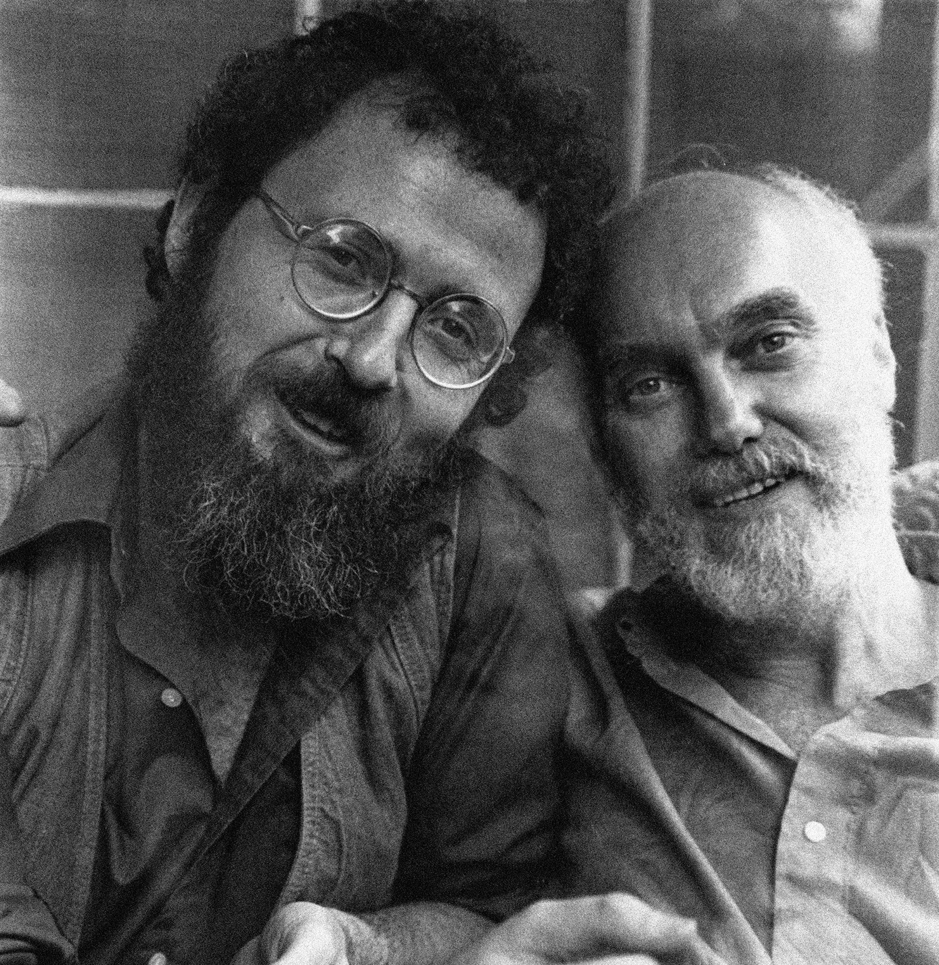 Sy Safransky and Ram Dass sit side-by-side and look into the camera.