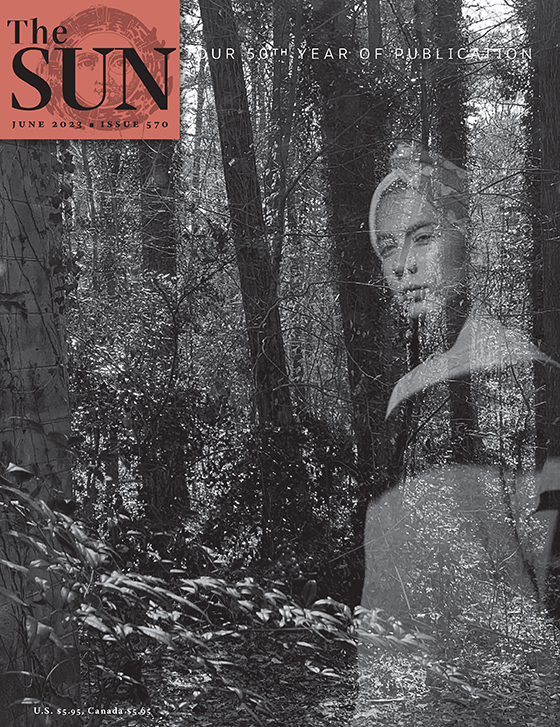June 2023 cover of The Sun. A girl stands near a window overlooking a wooded area. The photo was taken from a position behind her and the camera caught a ghostly reflection of her on the window that seems superimposed on the wooded area.