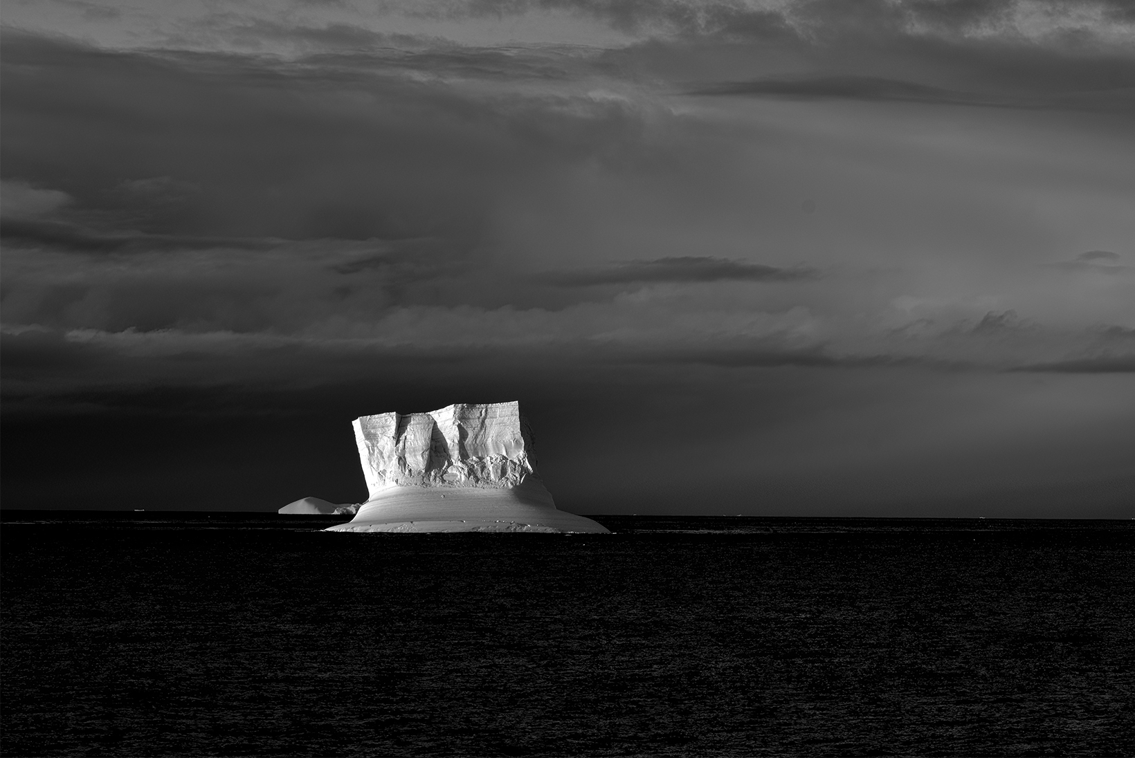 An iceberg, stark against the water and the cloudy skies, seen on an expedition to Antarctica.