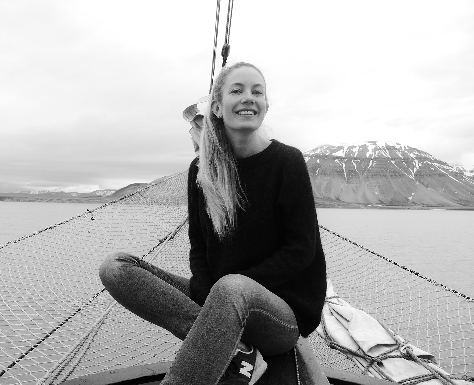 Synne Borgen sitting on the bow of the Antigua sailing near the northwestern shore of Billefjorden in Svalbard, Norway.