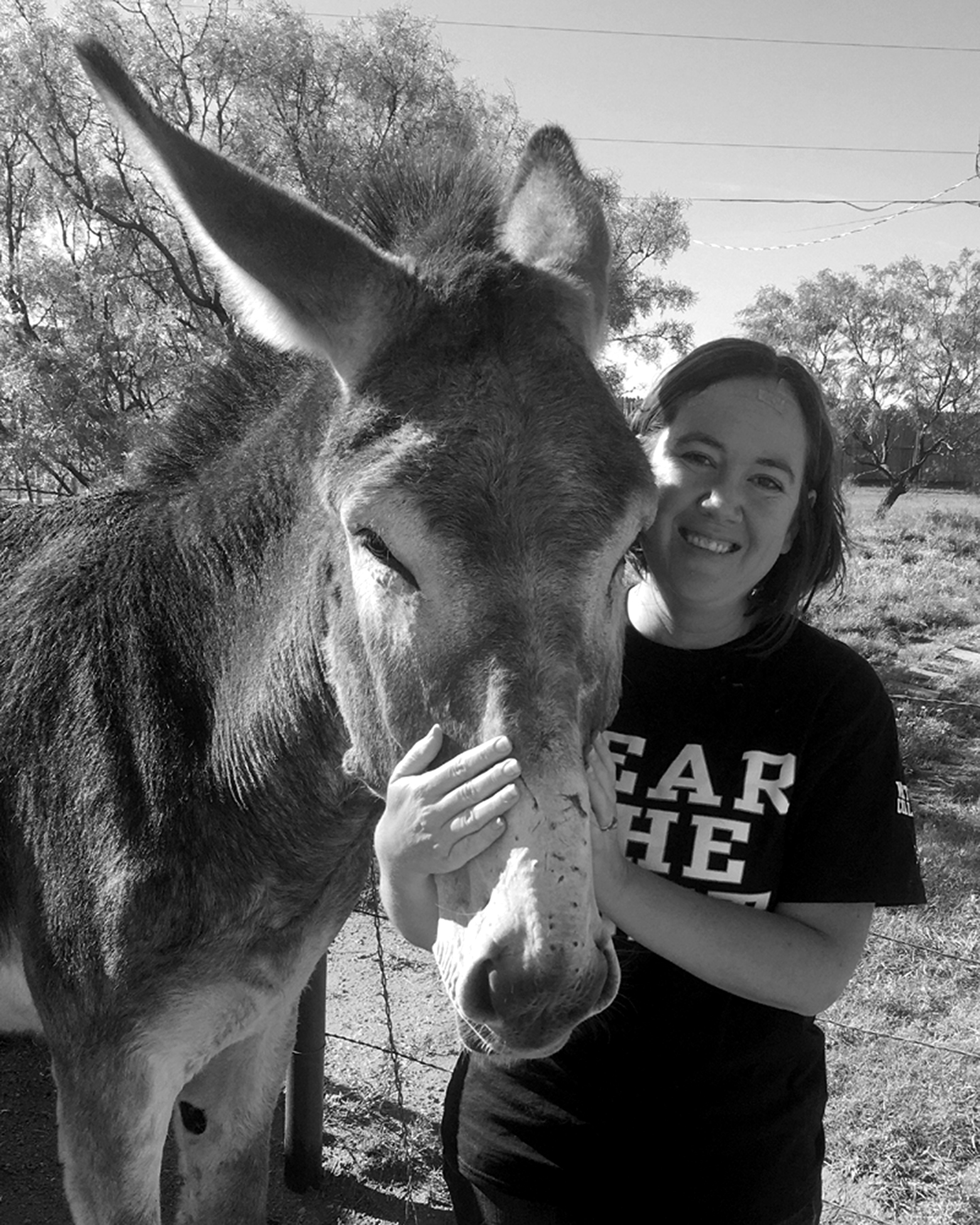 Chera Hammons smiles while holding Daisy, a mammoth donkey, by the muzzle.
