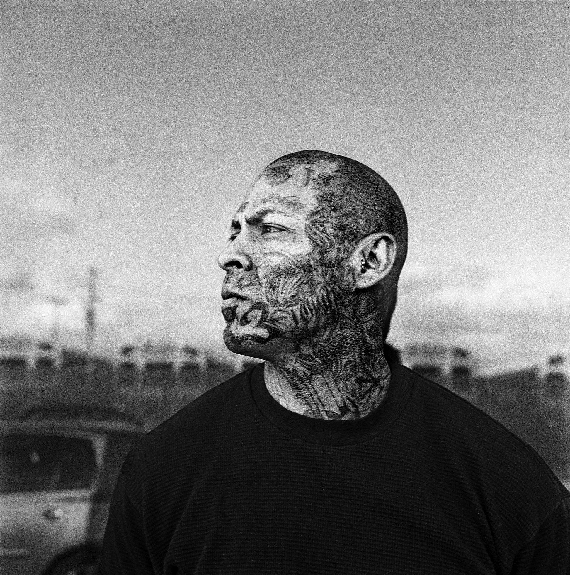 Close-up of the head and neck of a man in profile that are covered with tattoos.