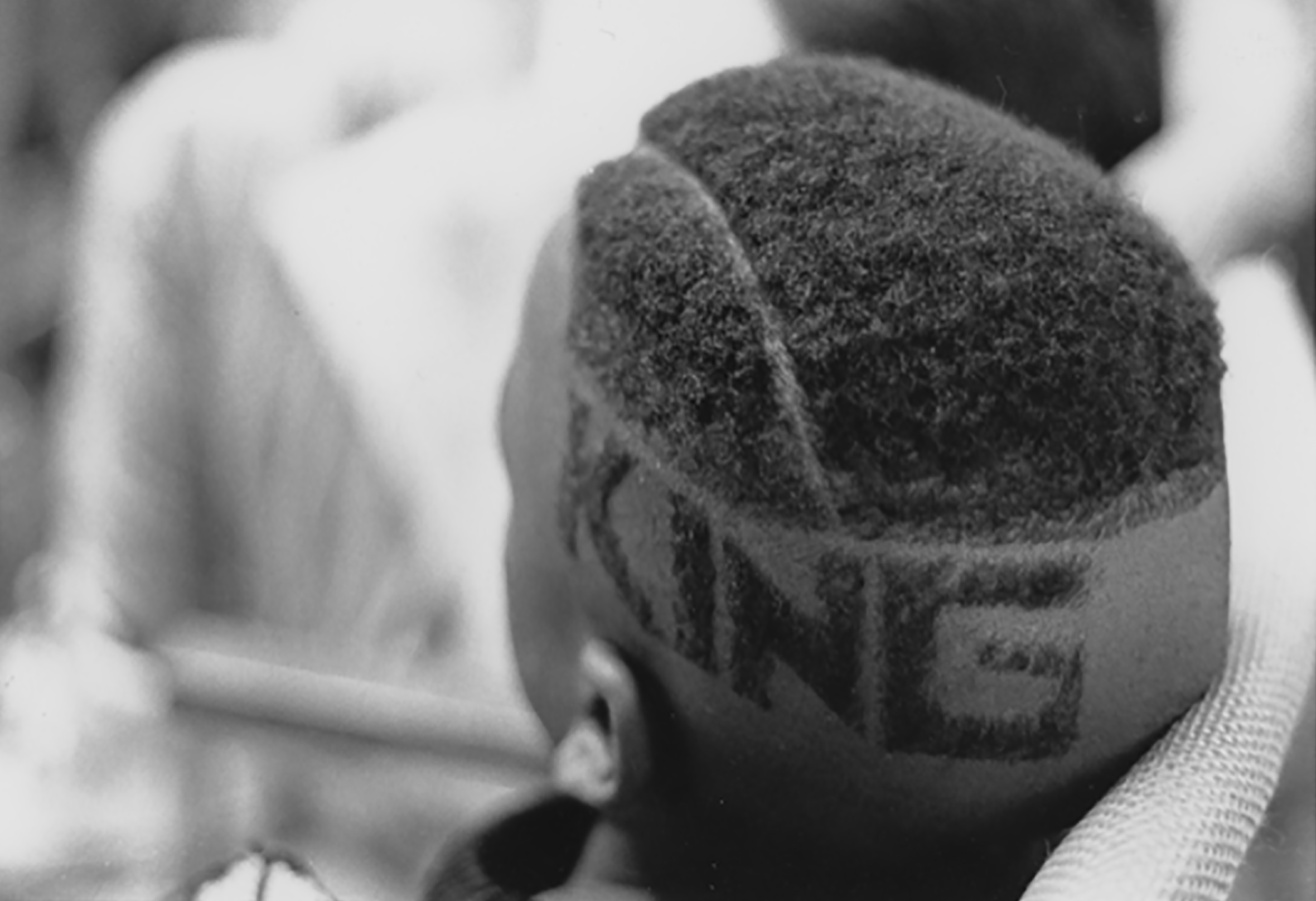 Close-up of the left side and back of the head of a man with a high fade haircut with a line with ”KING” spelled out in block letters of hair on the shaved part of his head.