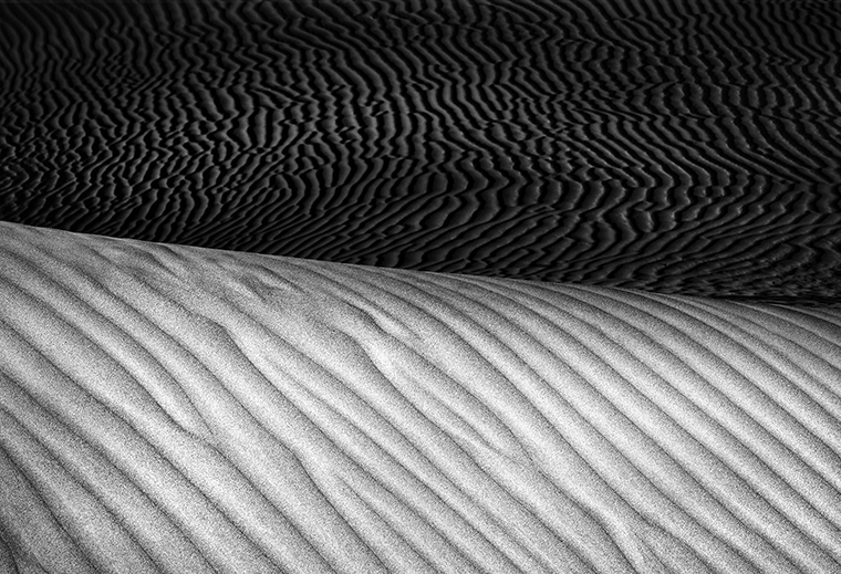 A landscape portrait of Mesquite Flat Sand Dunes in Death Valley National Park. Waves of sand fill the image.