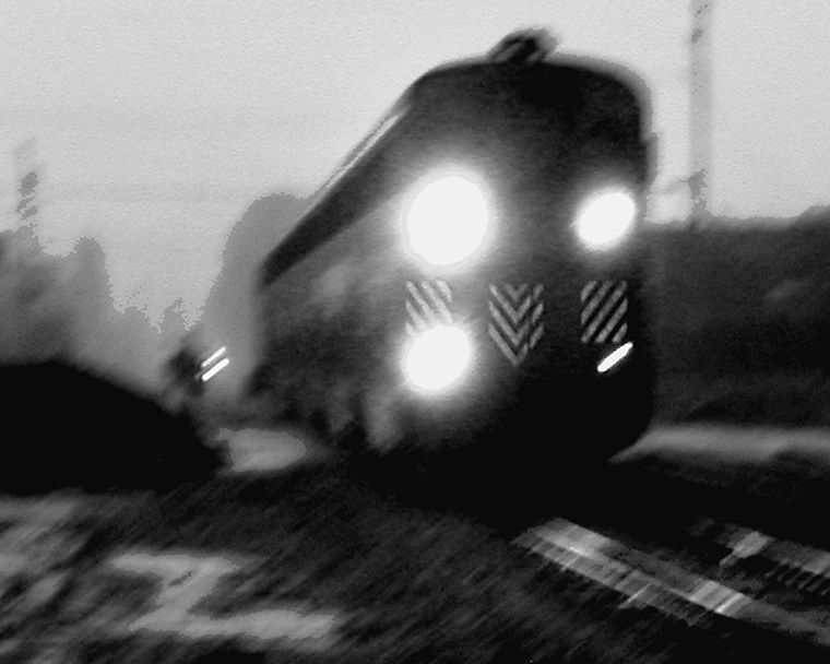 Blurry close-up of the first car of a train speeding down the tracks.