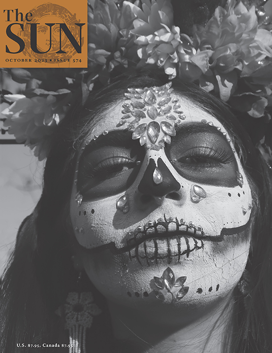 October 2023 cover of The Sun. A young woman dressed as La Catrina at a Día de los Muertos celebration. The top of her head is covered with large flowers and her face is covered in heavy white makeup and embellished with clear crystals.