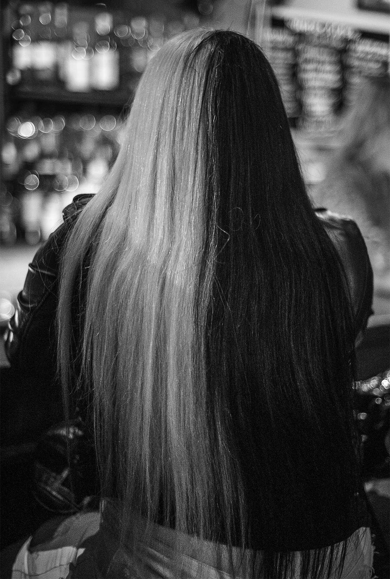 A woman sits at Sweetie’s Art Bar in San Francisco in 2020 with her back to the camera. She has waist-length, straight blond hair that covers her back.