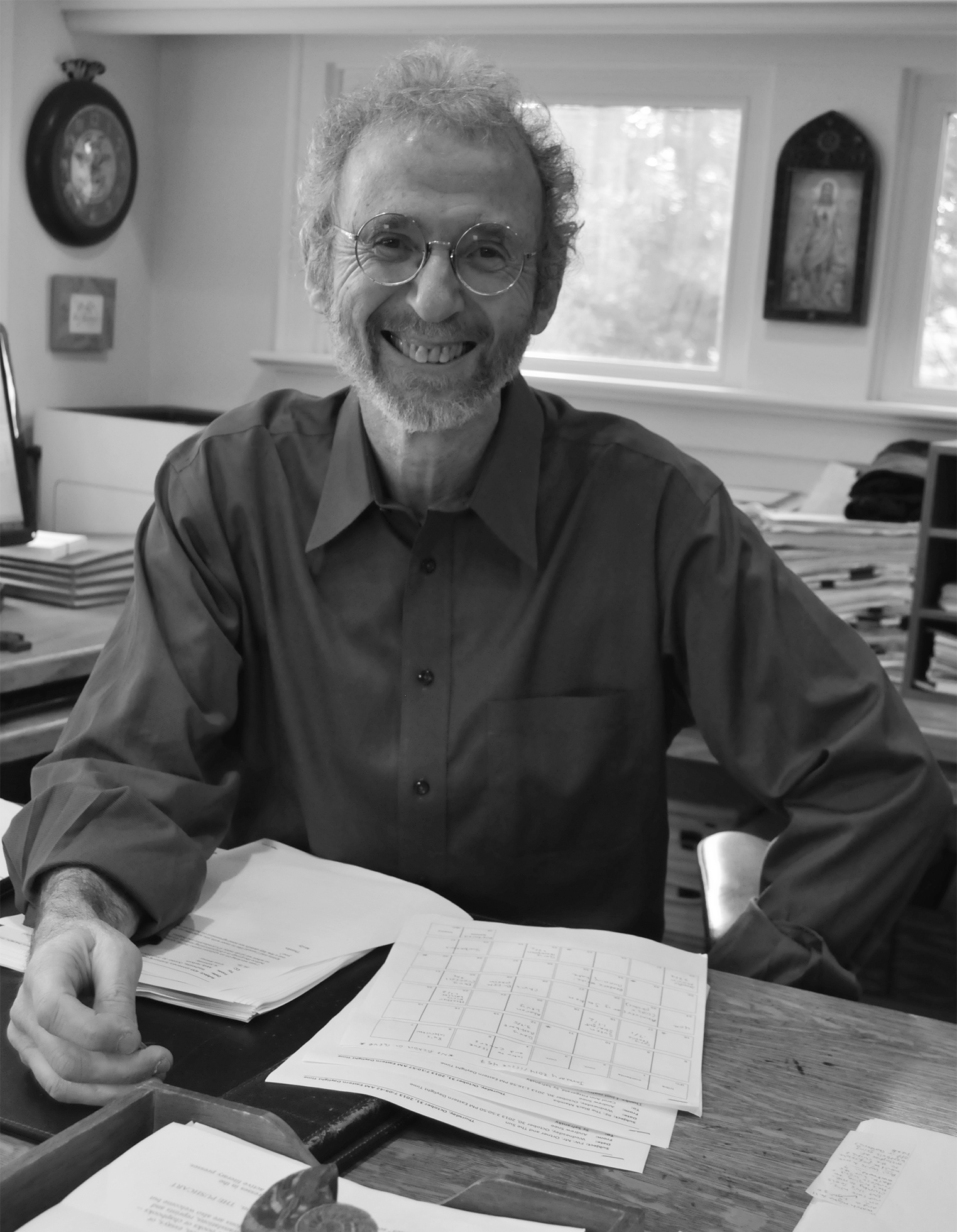 Sy Safransky sits at his office desk while smiling.