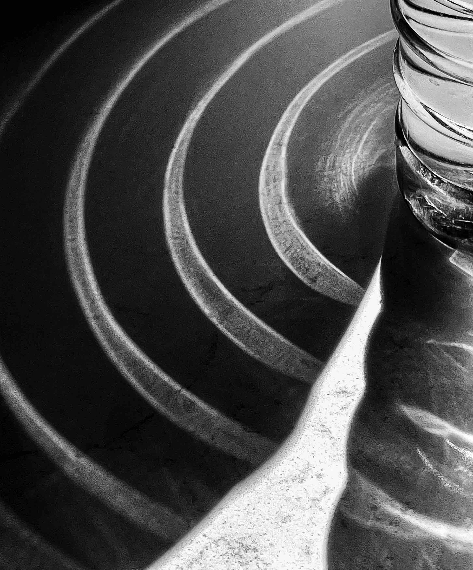 Concentric circles of light reflected on a kitchen counter from the rings on a clear plastic water bottle.