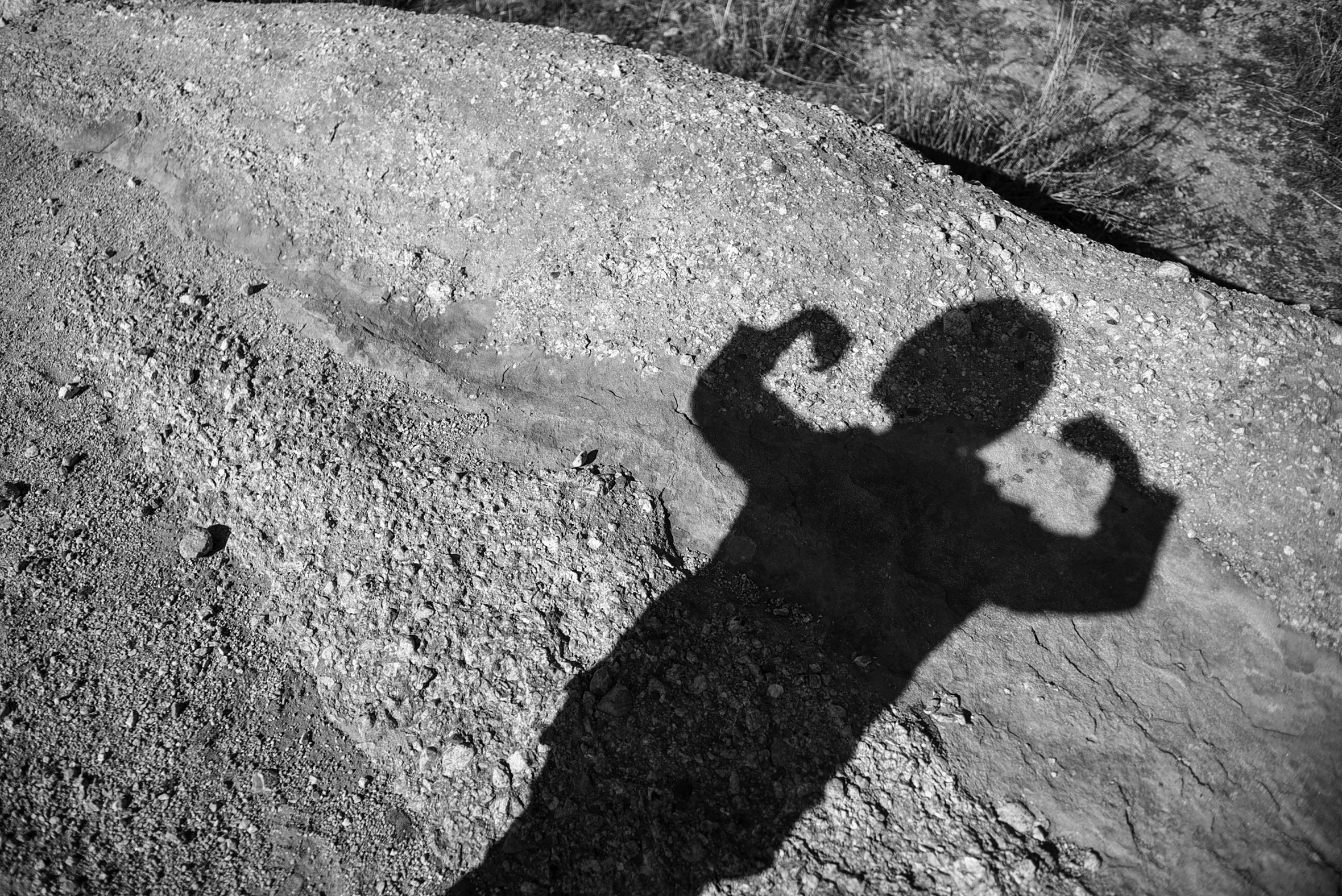 The shadow of a child flexing their arm muscles.