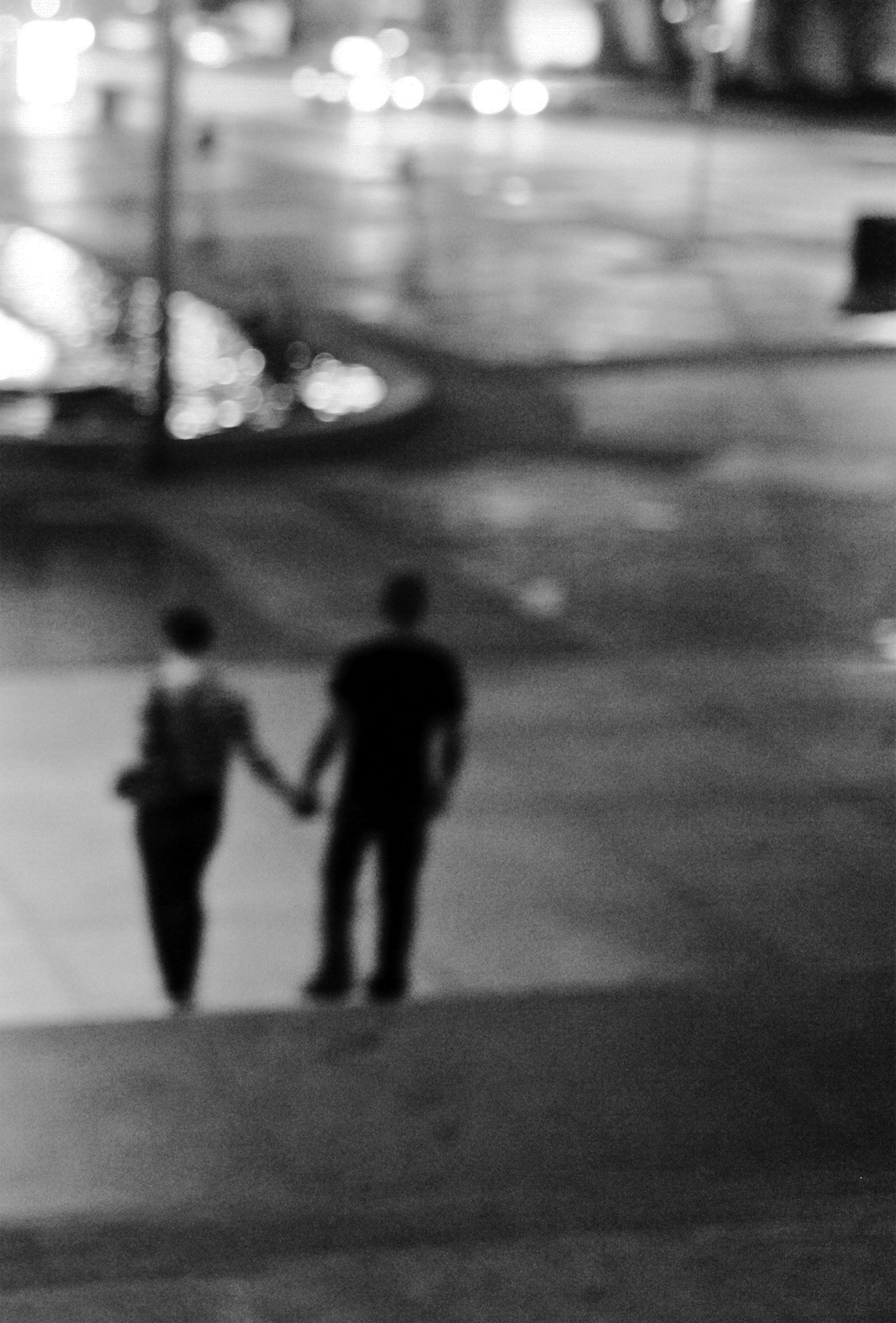 A blurry image of a couple holding hands while walking down Fifth Avenue in New York City.