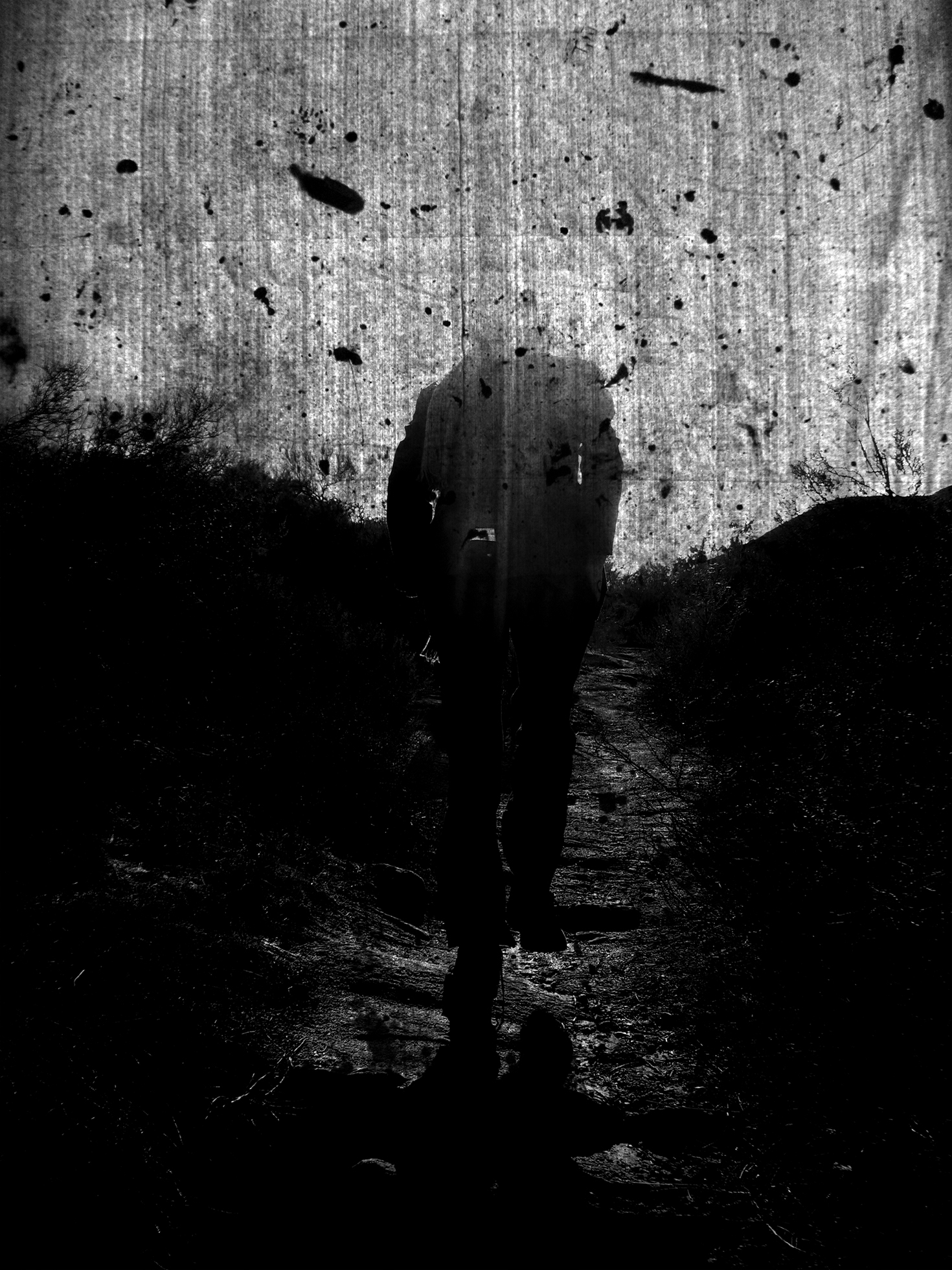 A headless man walks away from the camera on a path toward the horizon. The image is dark, including the sky where dark objects/spots swirl about.