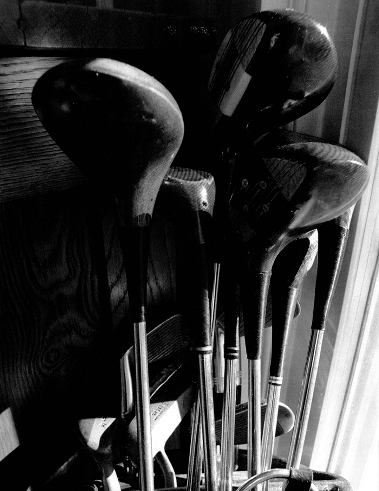 Close-up of the top portion of a set of golf clubs upright in a golf bag.