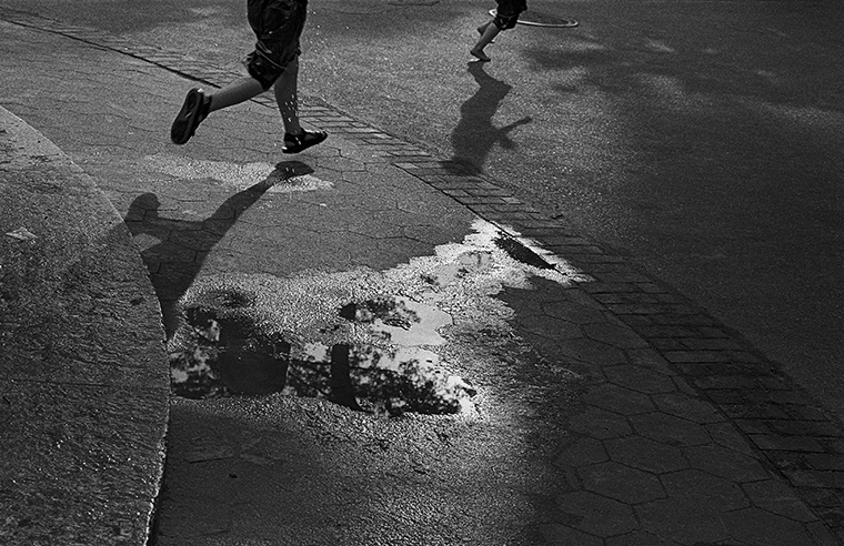 Two children run on pavement—only their legs are visible.
