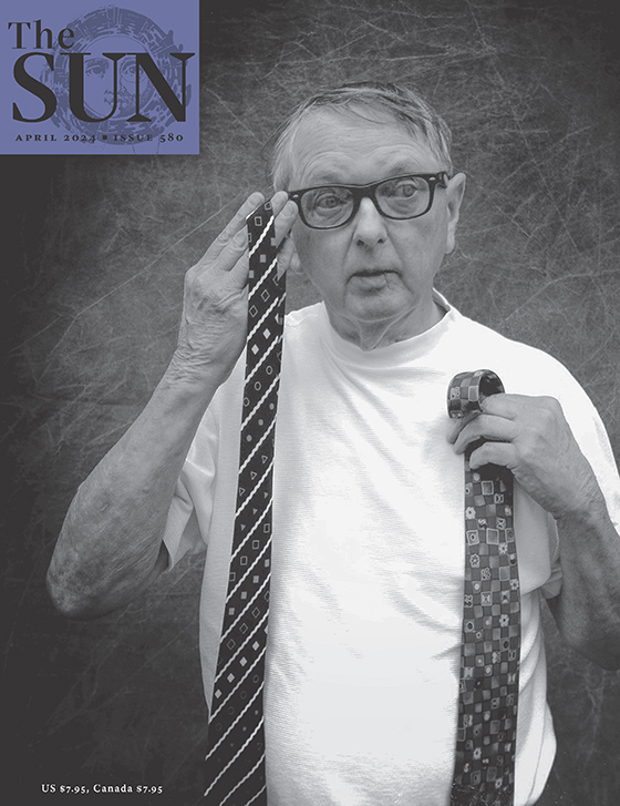 April 2024 cover of The Sun. An older man in a white T-shirt and dark-framed glasses holds up two neckties that he bought at the photographer’s estate sale.