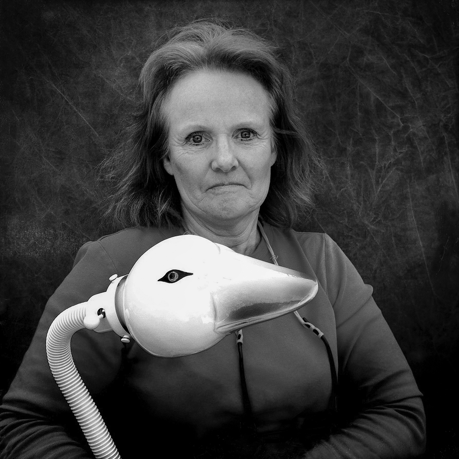 A woman holds a gooseneck lamp with a goose head.