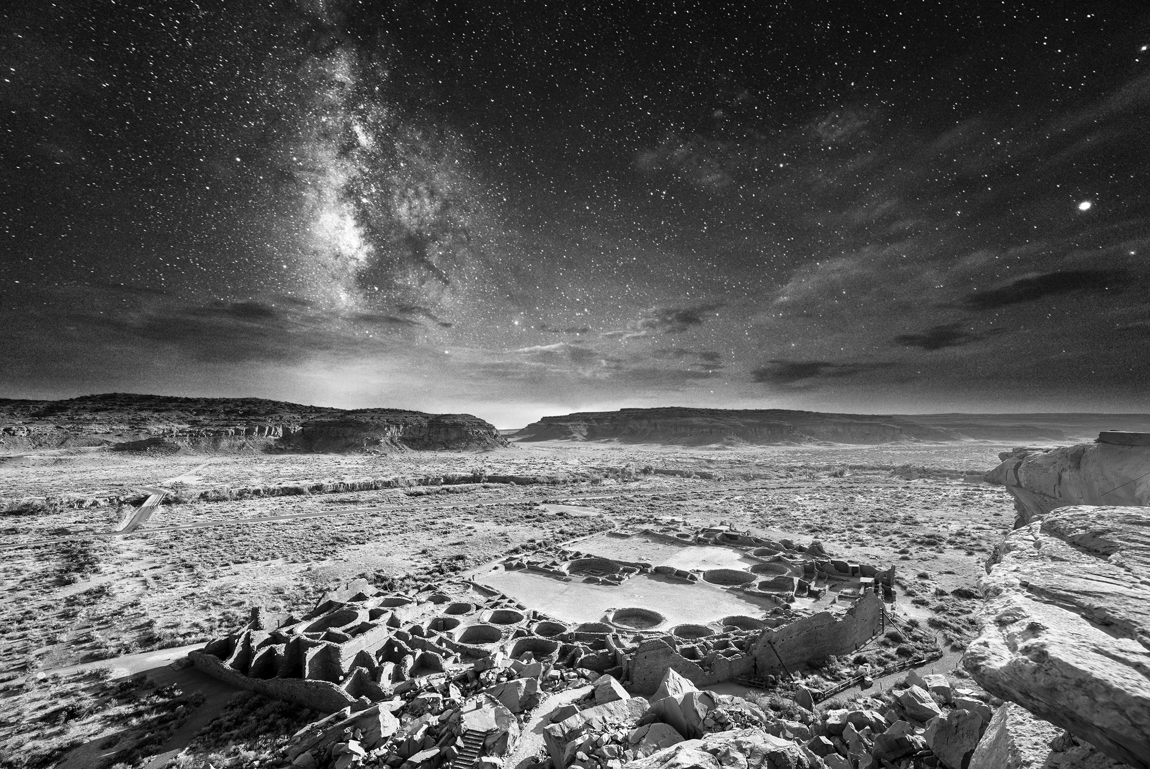 The photo titled “Ancient Nights: Evening at Pueblo Bonito” shows a top-down view of the Pueblo Bonito ruins and the surrounding landscape taken on a starry night.