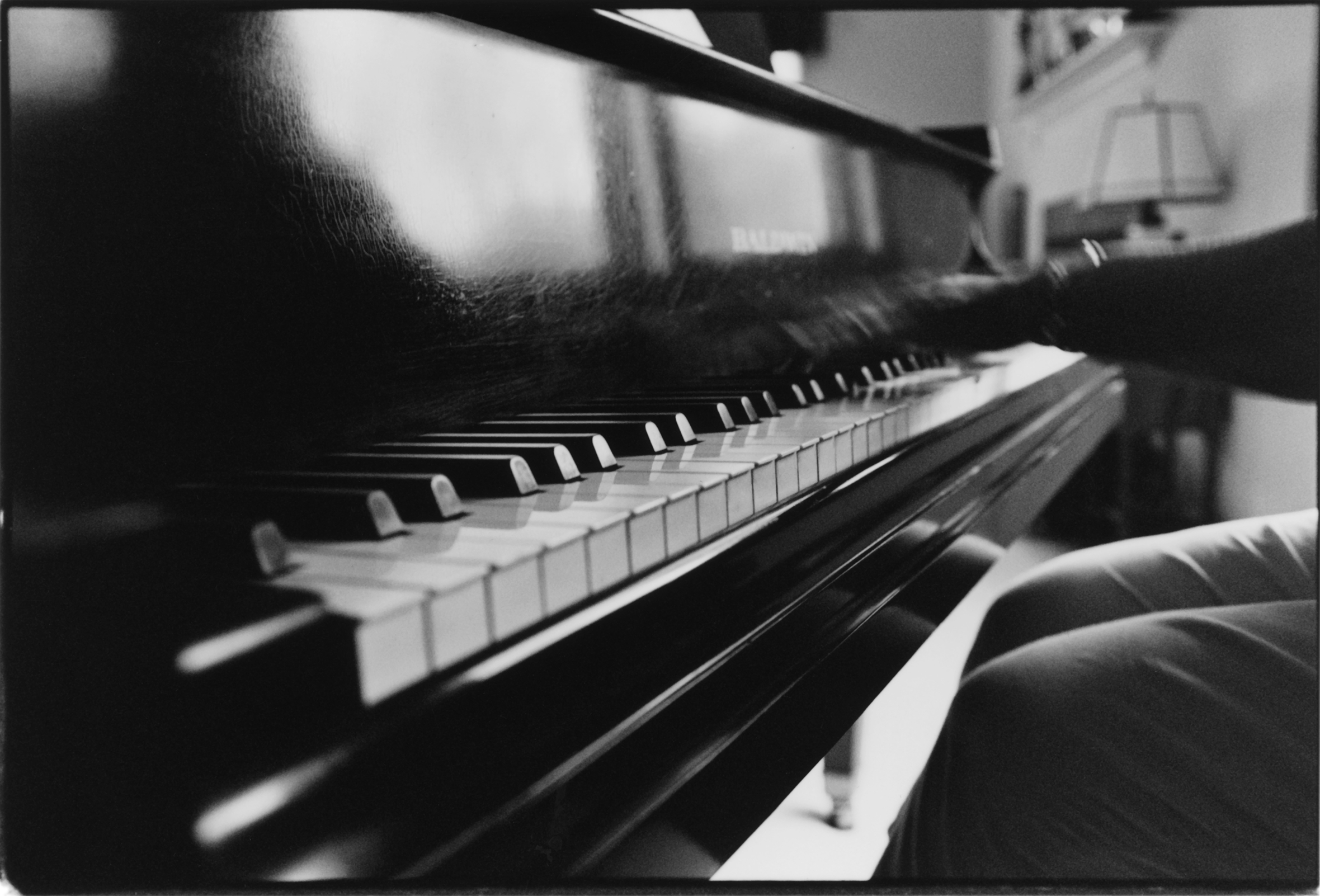 Close-up of a piano and the hands and knees of the person playing it.